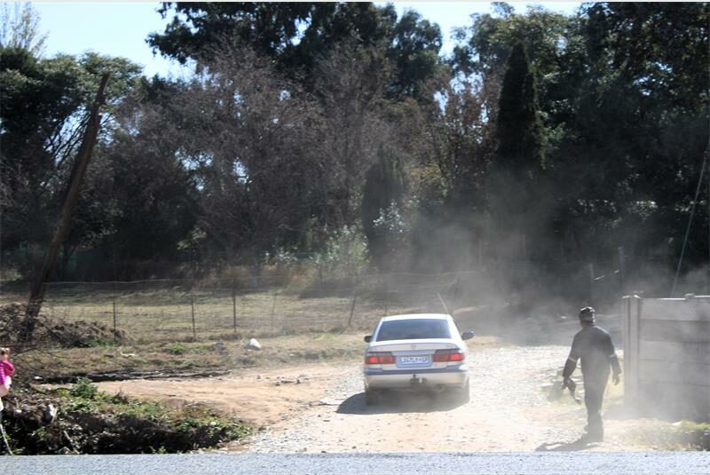 A man is walking down the road with a car.