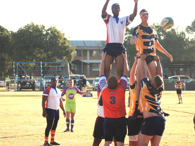 A group of men playing rugby in a field.