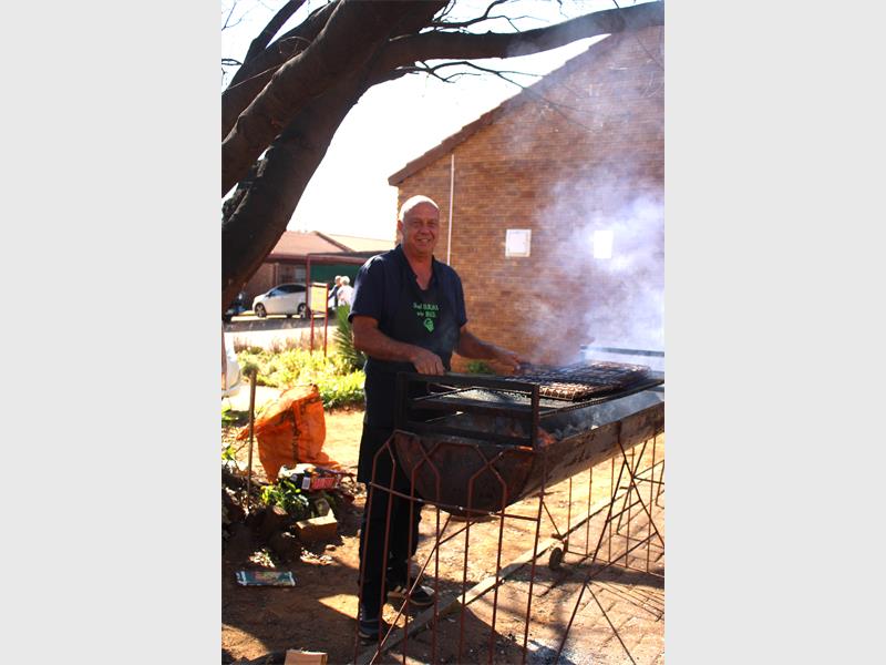 A man standing in front of a grill with smoke coming out of it.