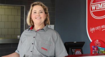 A woman in a restaurant standing at the counter.