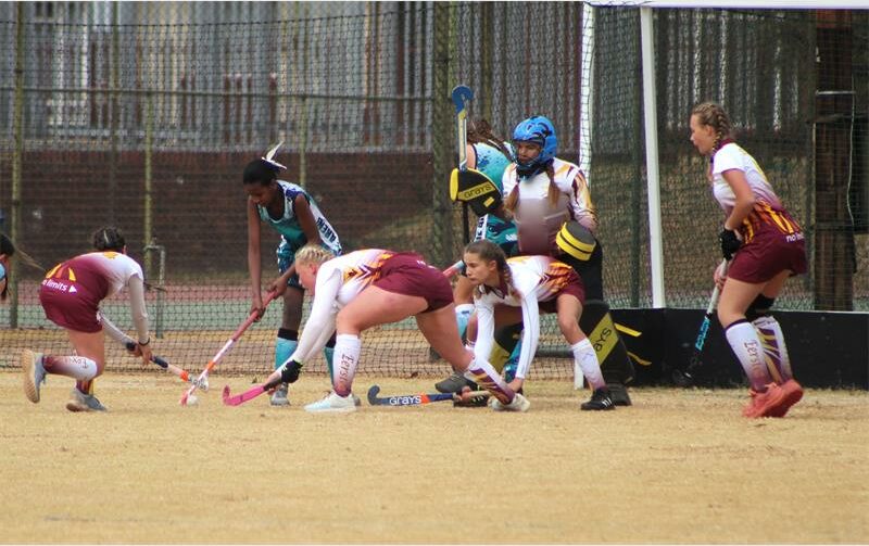 A group of women playing field hockey on a field.