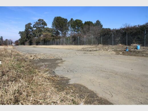 A dirt road with a fence and a blue fence.