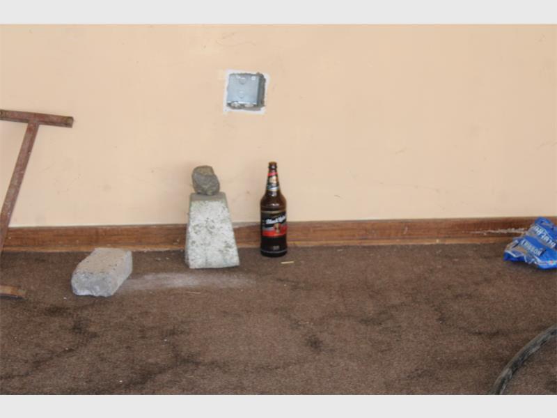 A bottle of beer and a chair sitting on the floor.