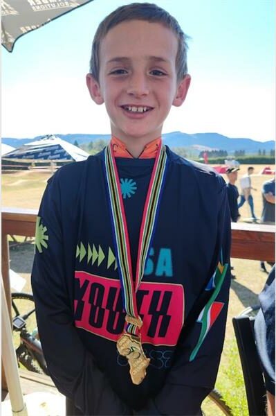 A boy wearing a medal and standing next to a bike.
