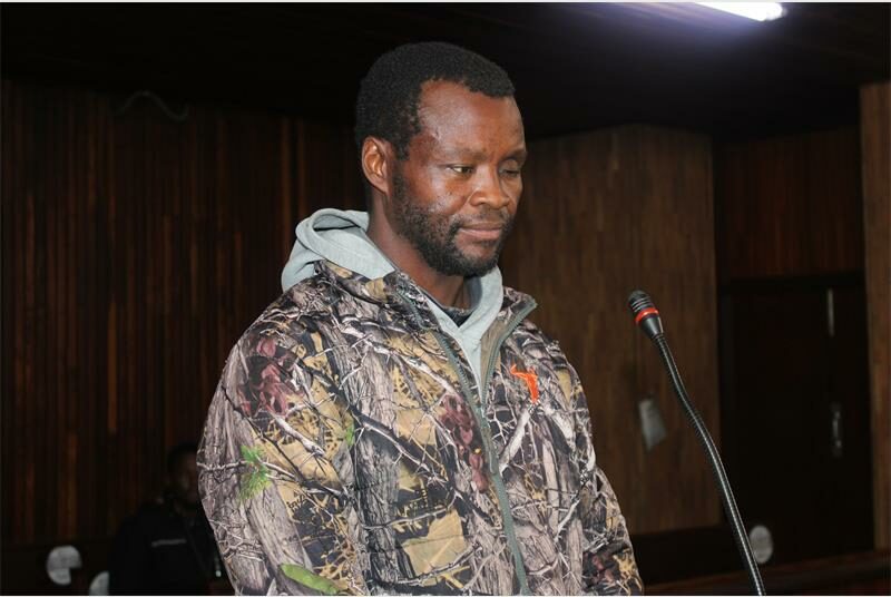 A man in camouflage jacket standing at a podium.