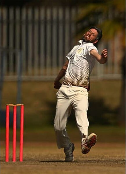 A man in white shirt and pants is about to throw the ball.