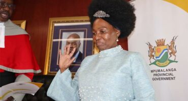 A woman in a blue dress and white shirt is standing next to a man.