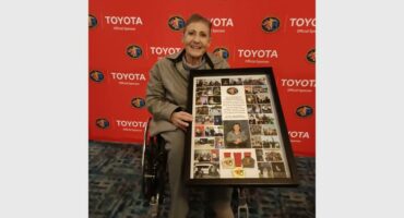 A woman in a wheelchair holding a framed picture.