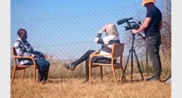 A man and woman sitting in chairs with a camera.