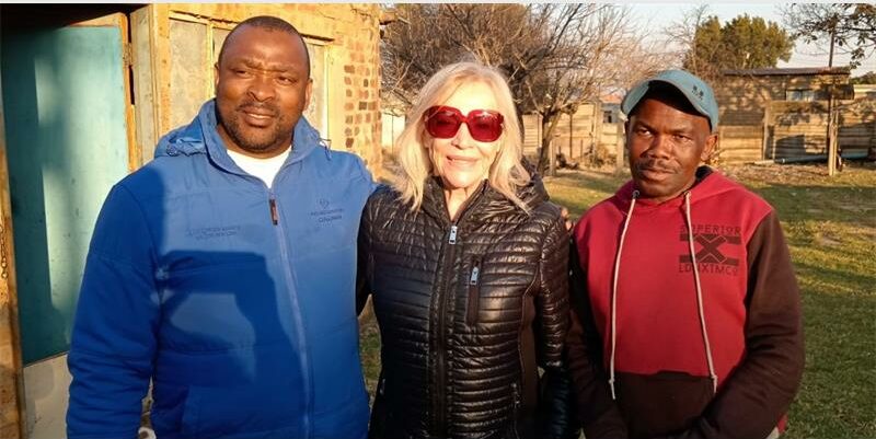 Three people standing together in front of a house.