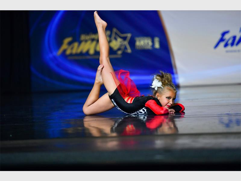 A young girl doing a gymnastics routine on a stage.