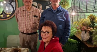 Three people standing in front of a table with plants.