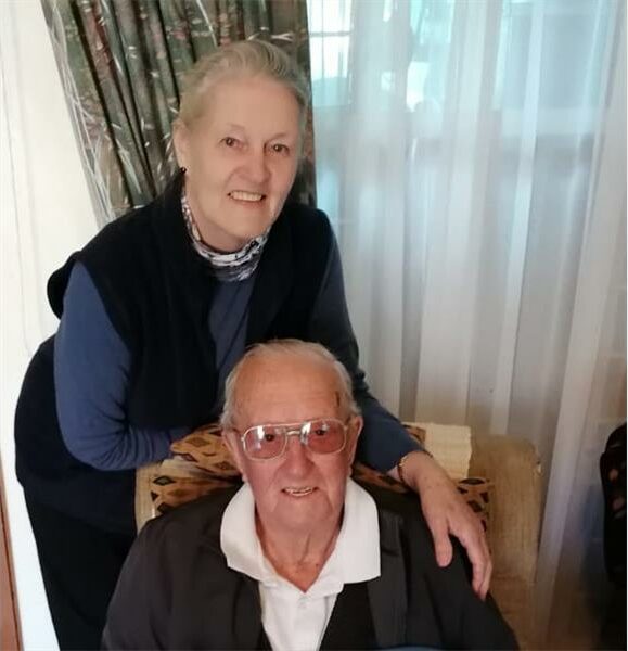 An older man and woman sitting on a couch.