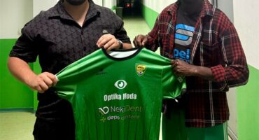 Two men standing next to each other holding a green shirt.