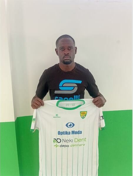 A man holding up a white and green shirt.