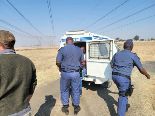 Police officers walking down a dirt road with a truck.