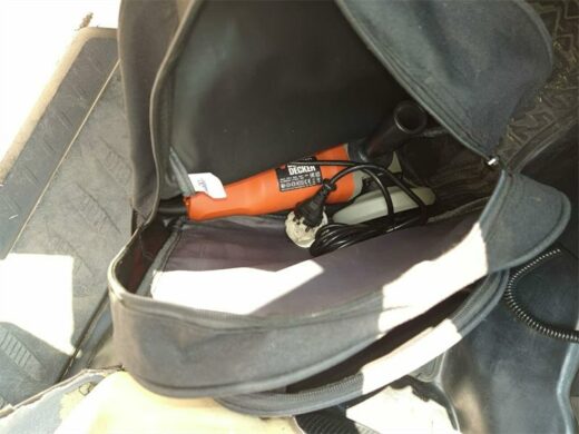 A black bag with a small orange tool inside.