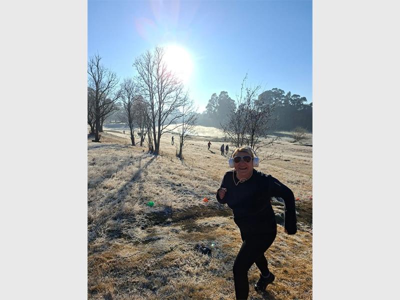 A woman running in the snow on a sunny day.