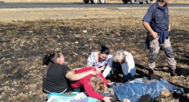 People are gathered around a body in the field.