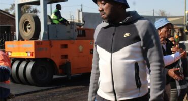 A man standing next to a construction vehicle.