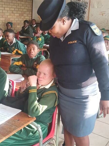A police officer is helping a student in a classroom.