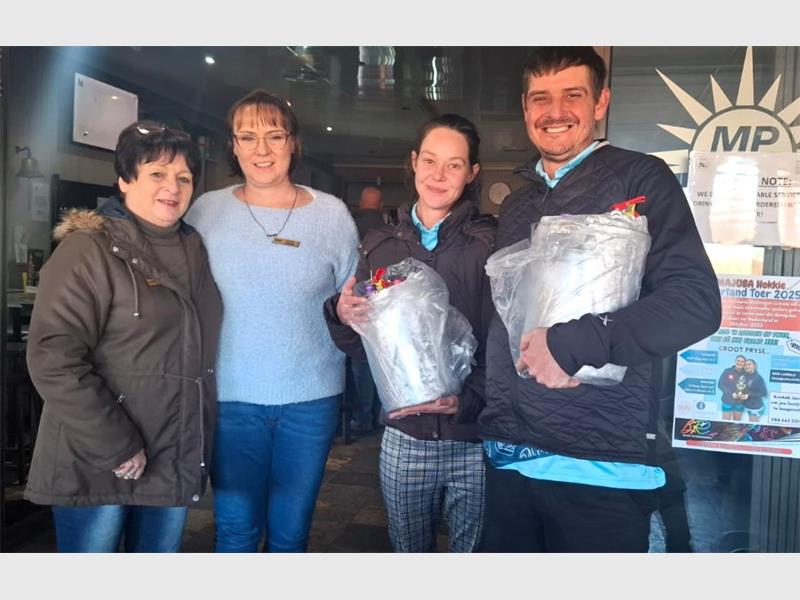 Three people holding bags of food in front of a store.