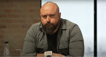 A bald man with a beard sitting at a table.