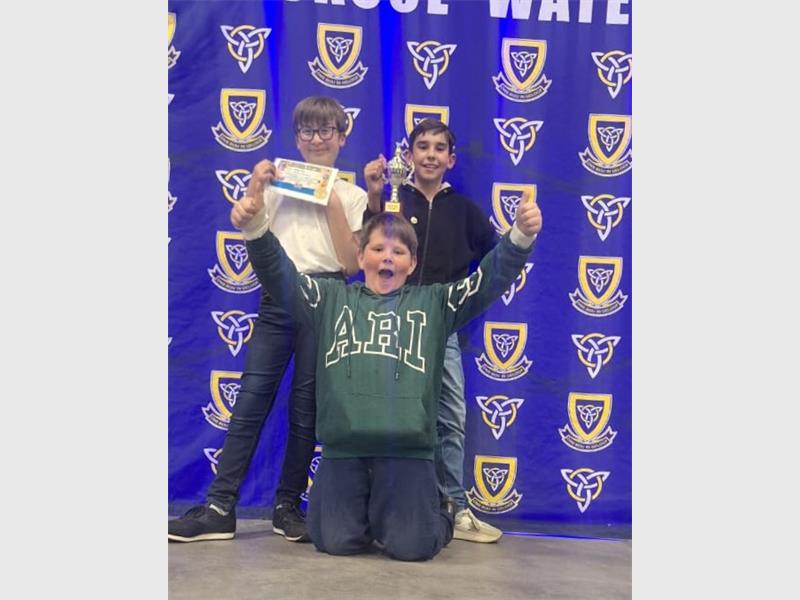 Three boys pose for a picture with their trophies.