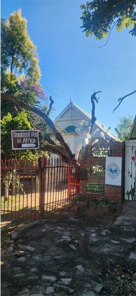 The gate to the house is open and there is a tree in front of it.