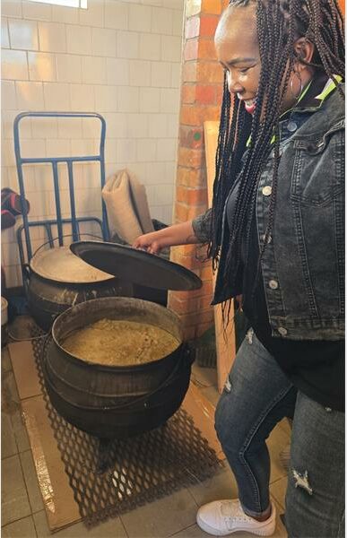 A woman with dreadlocks pouring a pot of food.