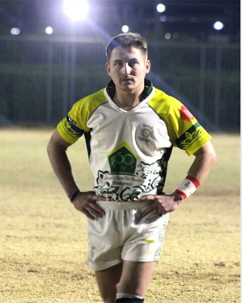 A man in a rugby uniform standing on a field.