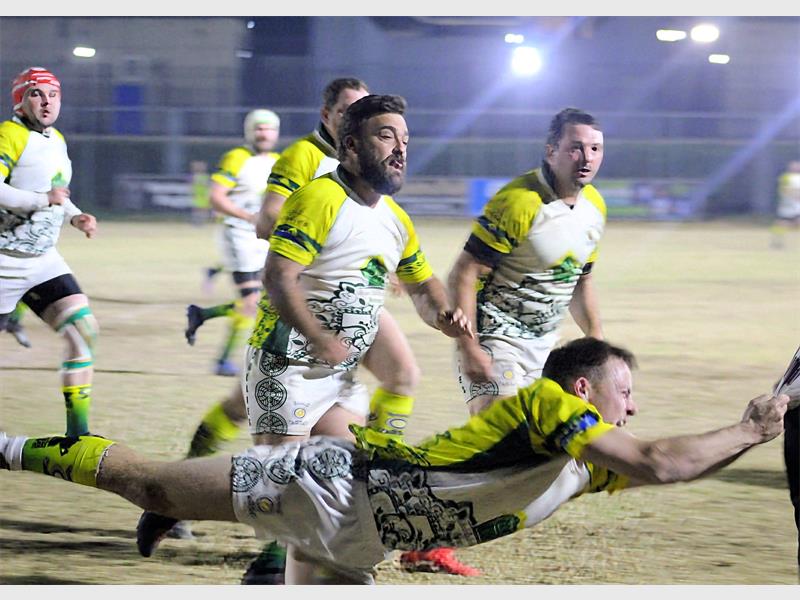 A rugby player is diving for the ball.