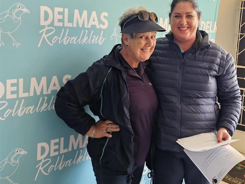 Two women standing next to each other holding papers.