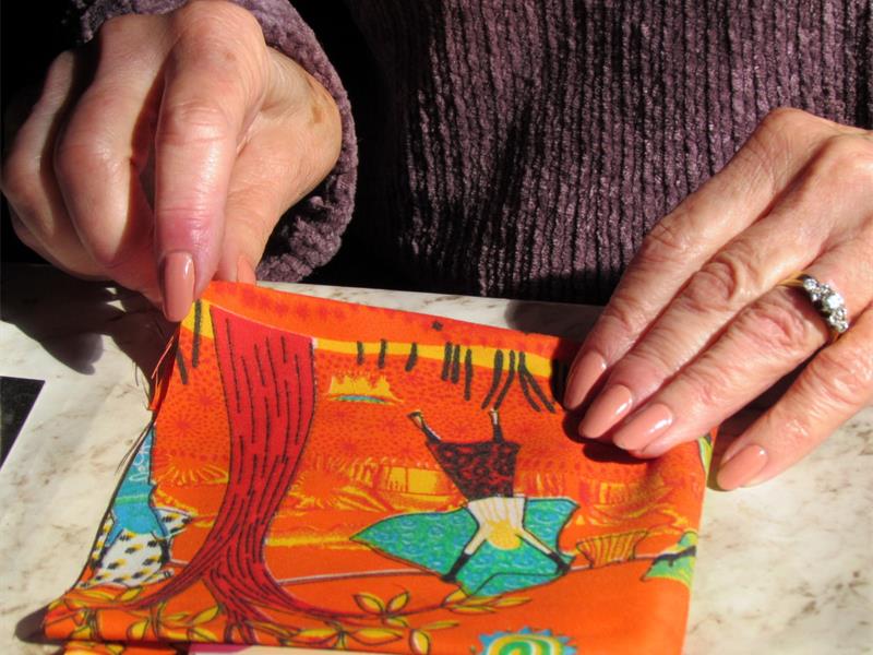 A woman is cutting fabric on a table.
