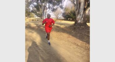 A man in red running on a dirt road.