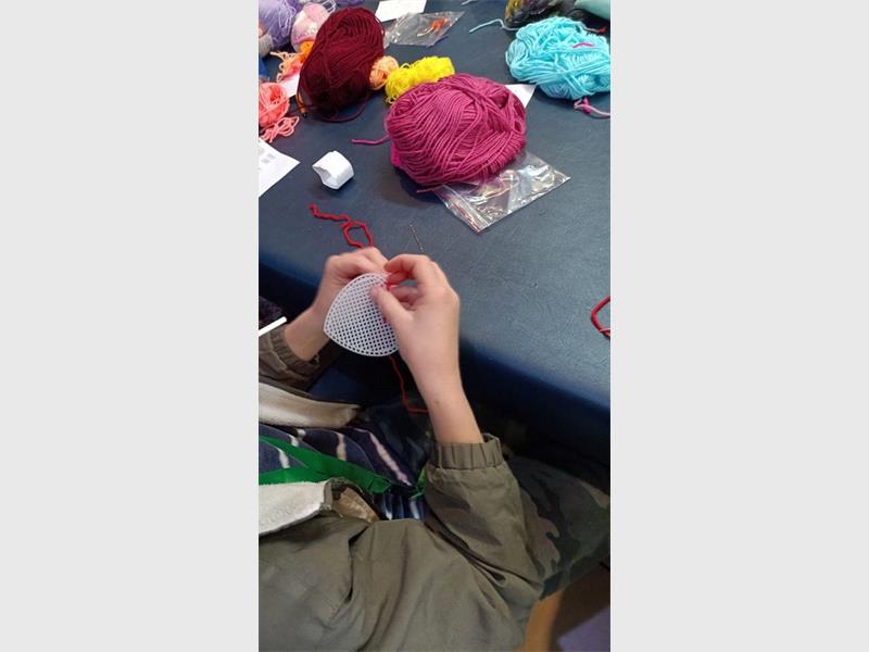 A person is knitting on a table with yarn.
