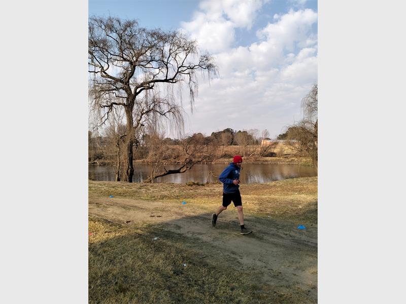 A man is running on a trail near a lake.