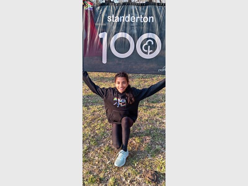 A woman is kneeling down holding a sign that says 100.