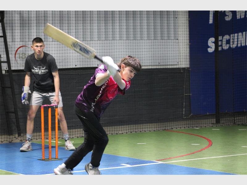 A young boy is hitting a cricket ball.