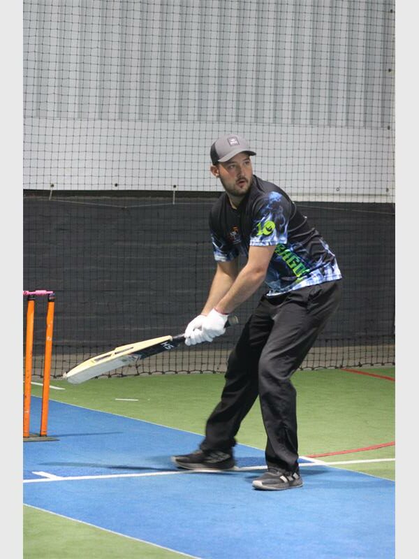 A man in a baseball cap is hitting a ball.