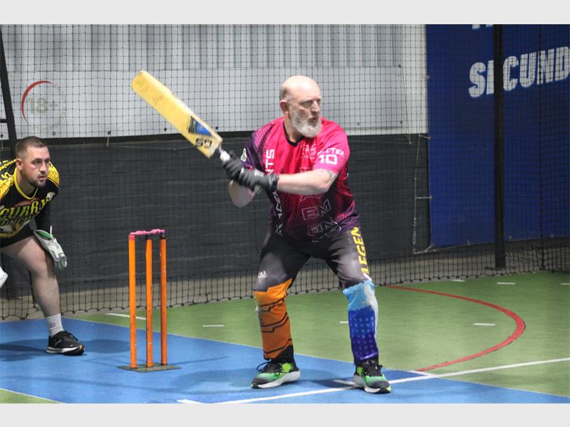 A man with a beard and a bat is playing cricket.