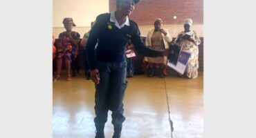 A woman in uniform holding a book in front of a crowd.