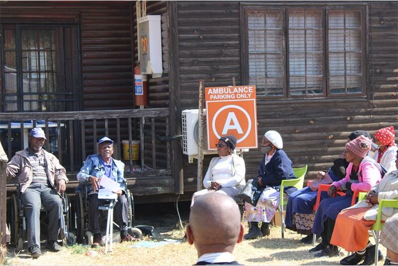A group of people sitting outside a house.