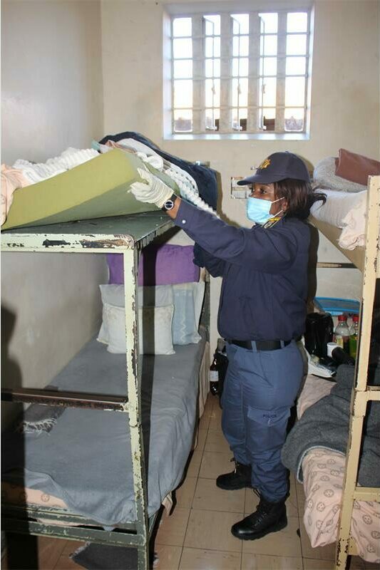 A woman in a blue uniform is putting a bed on a bunk bed.