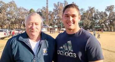 Two men standing next to each other in a field.