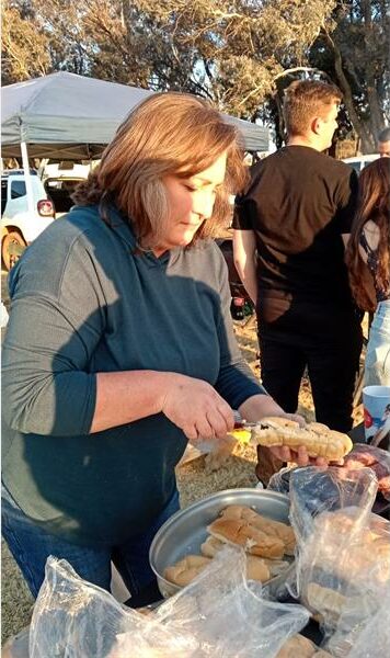 A woman is preparing food at an outdoor event.