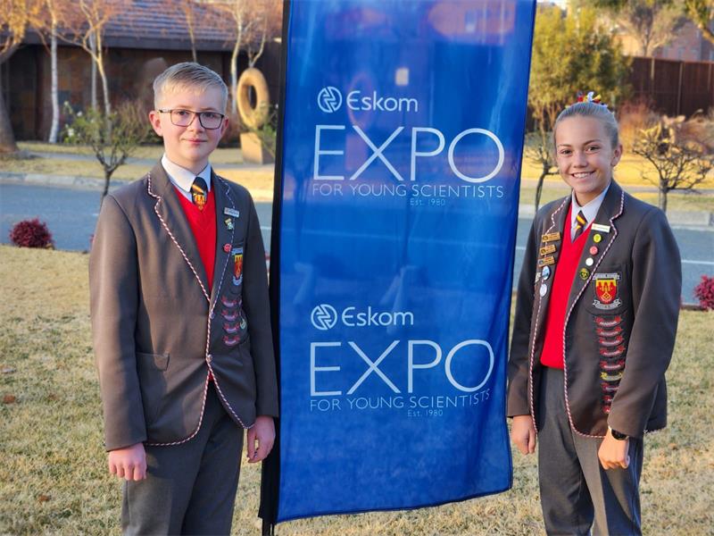 Two young boys standing next to a sign that says expo.