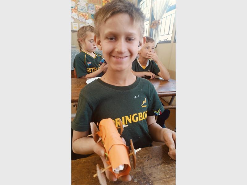 A boy smiles while holding a toy airplane.