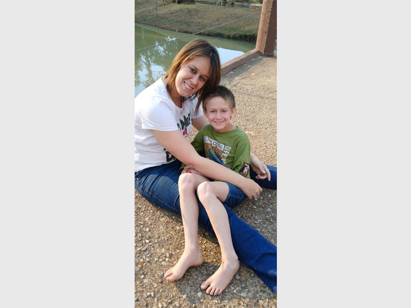 A woman and a young boy sitting on the ground.