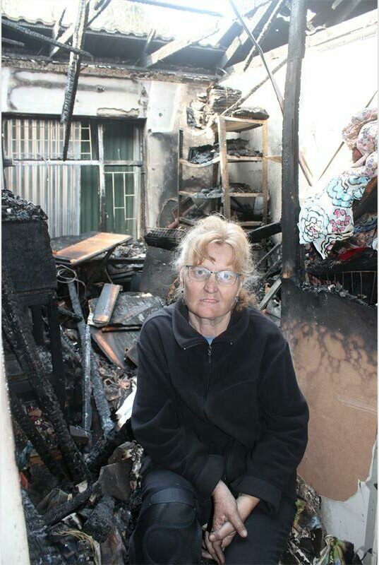 A woman sitting in a burned out building.